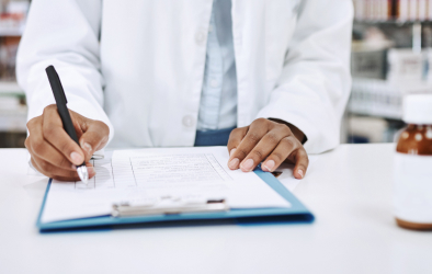 Doctor writing on a prescription pad.