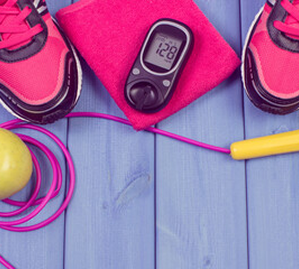 Glucometer with pink lanyard placed on a surface.