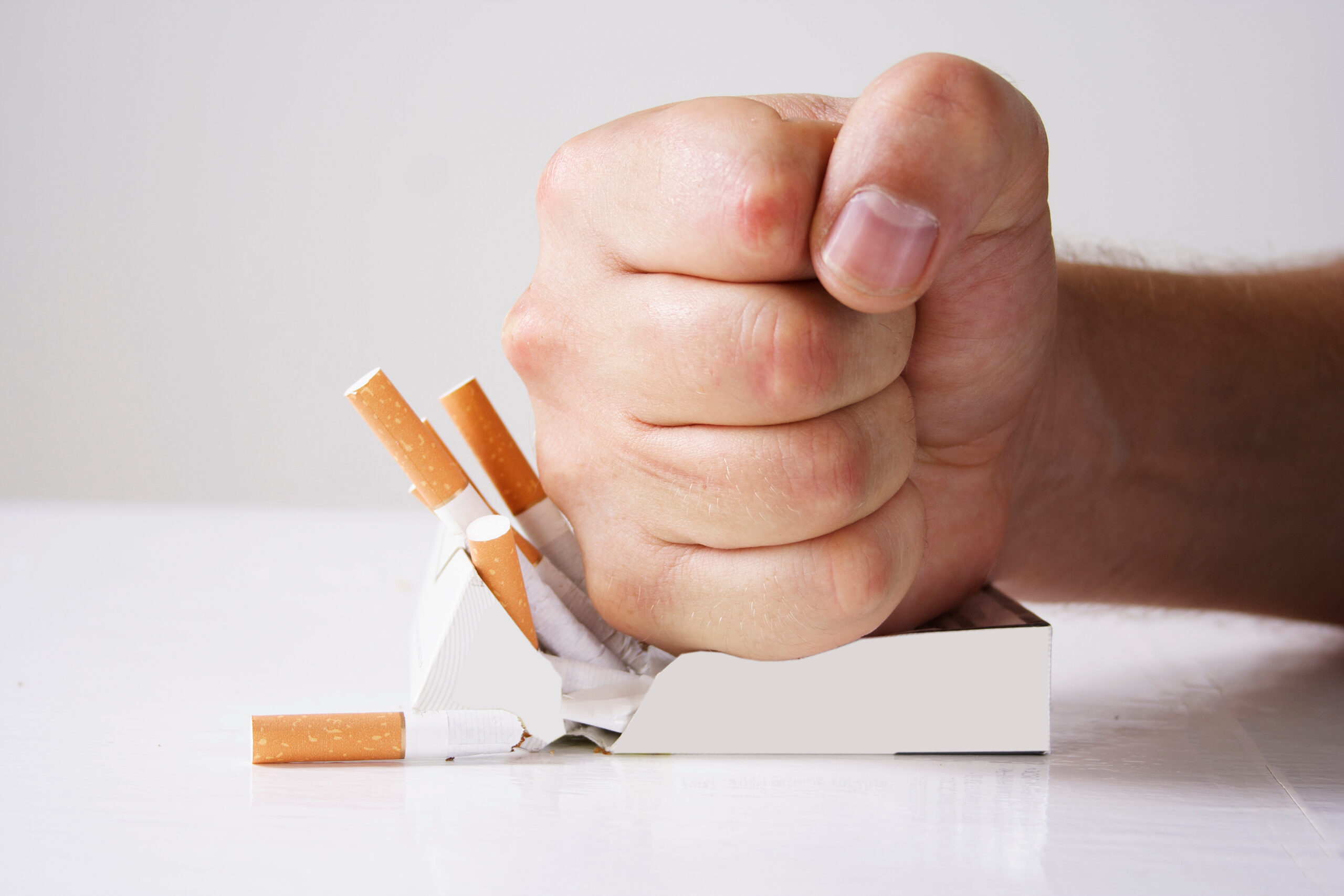 Hand crushing cigarettes over white background